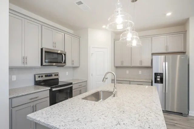 a kitchen with kitchen island a sink stainless steel appliances and cabinets