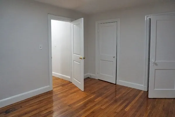 an empty room with wooden floor and closet area