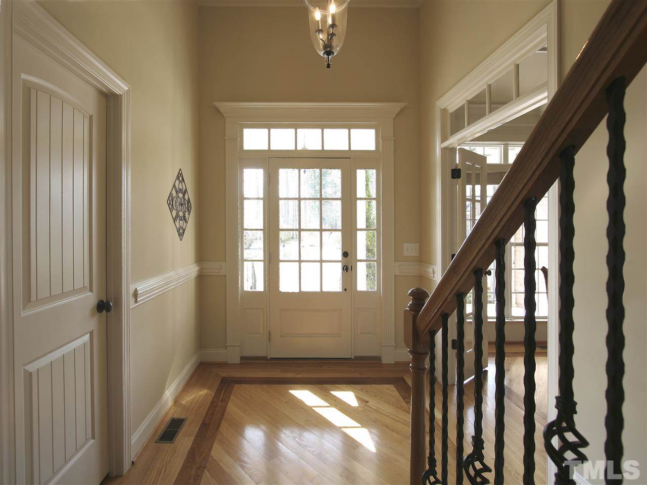 Gracious foyer. Beautiful inlaid wood floor. Front door has transom and sidelights. French doors to dining room are seen to the right (also with transom).