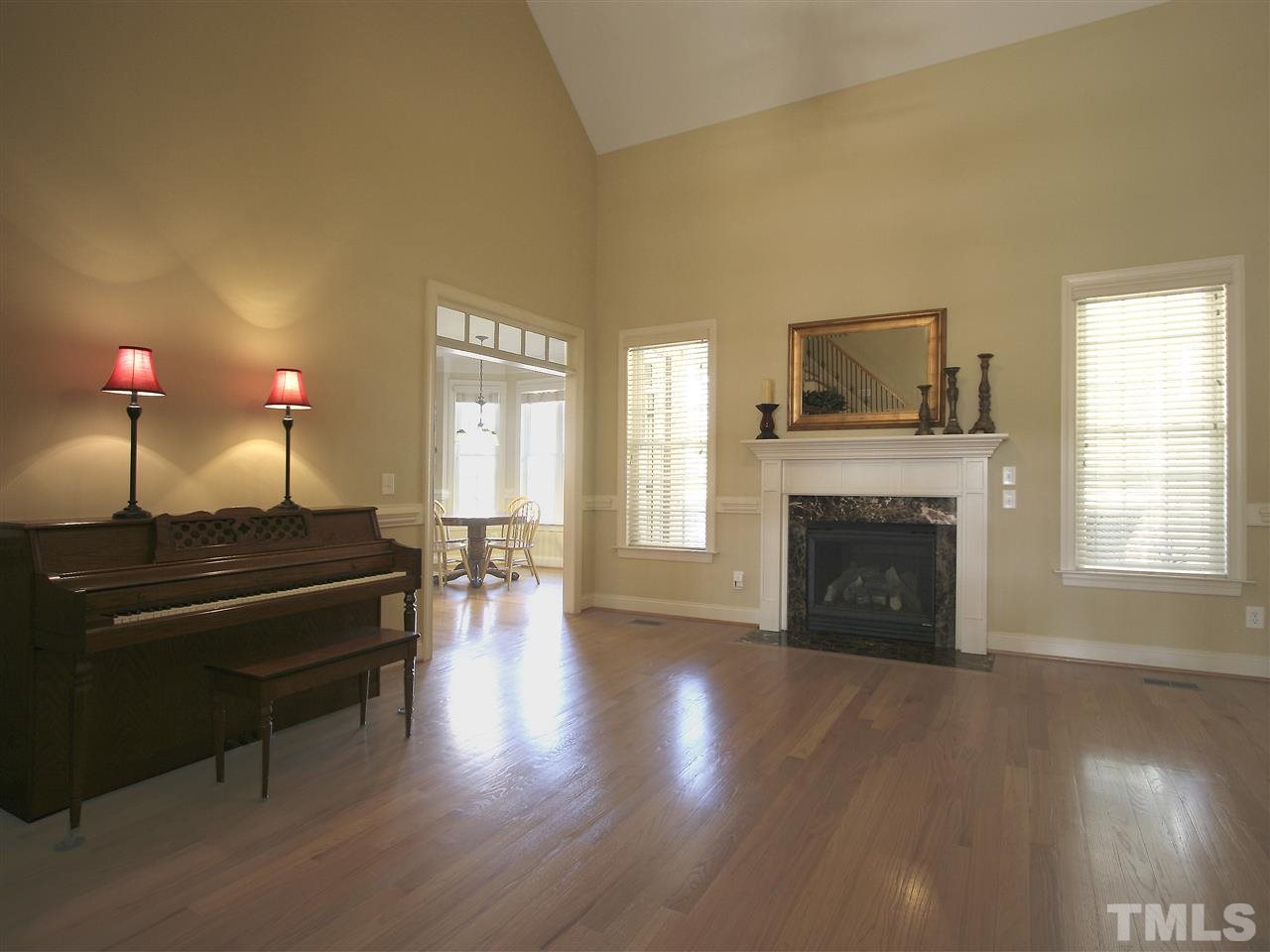 1205 Verde Farm Road Raleigh, NC 27603 - Photo 9 of 25 Living room has soaring ceiling, hardwood floor, and gas-log fireplace with marble surround and detailed mantel.