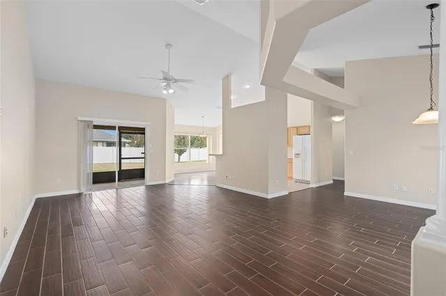 a view of an empty room with wooden floor and a ceiling fan