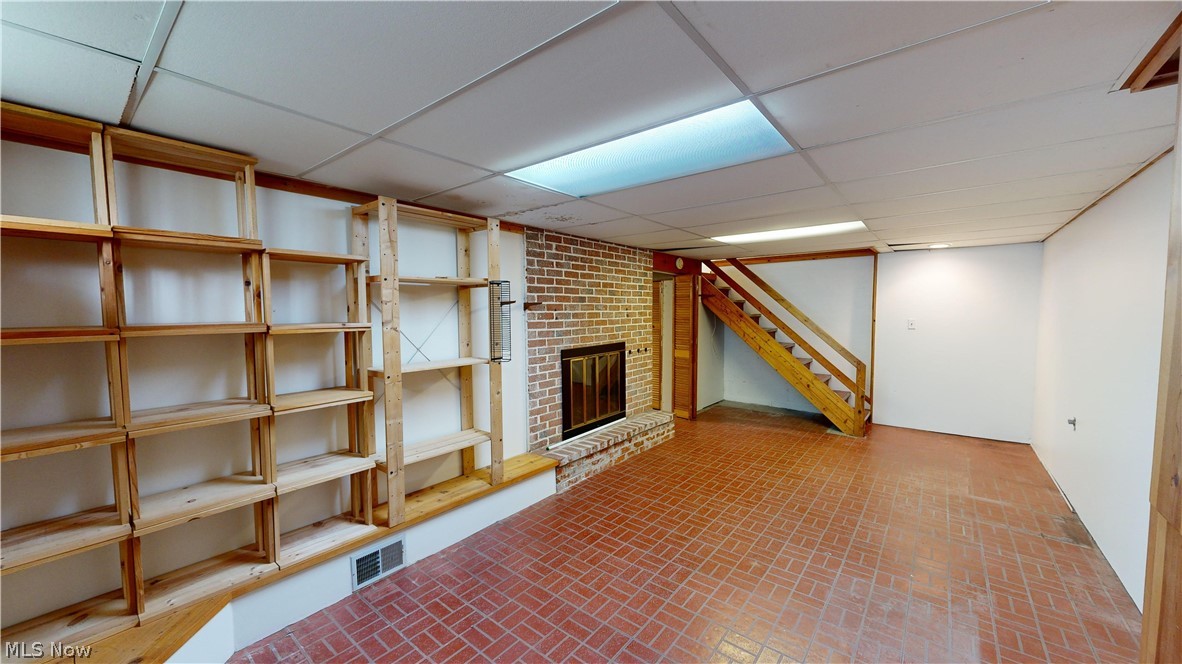 1508 Edgefield Road Lyndhurst, OH 44124 - Photo 20 of 28 Basement with brick wall, a fireplace, and a drop ceiling