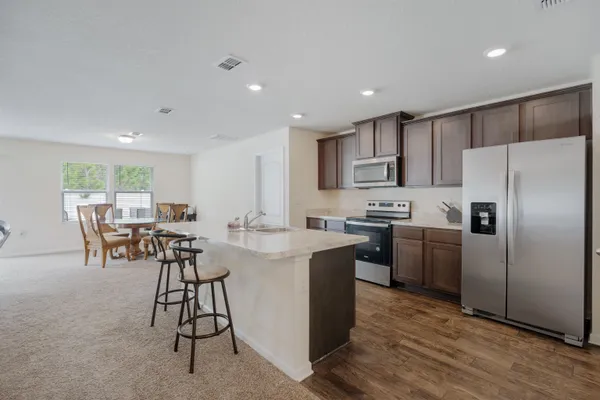 a kitchen with stainless steel appliances kitchen island granite countertop a refrigerator a stove a sink a dining table and chairs