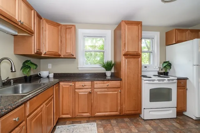 a kitchen with granite countertop a refrigerator sink stove and microwave