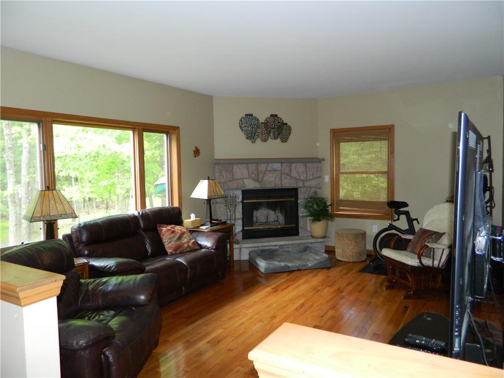 328 Pin Oak Road Stroudsburg, PA 18360 - Photo 14 of 37 A cozy living area showcases a stone-faced fireplace with a warm wood hearth and rich hardwood flooring.