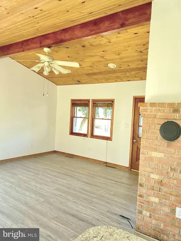 a view of an empty room with wooden floor and a ceiling fan
