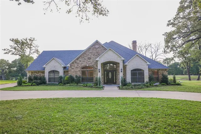 a view of a house with a yard and large trees