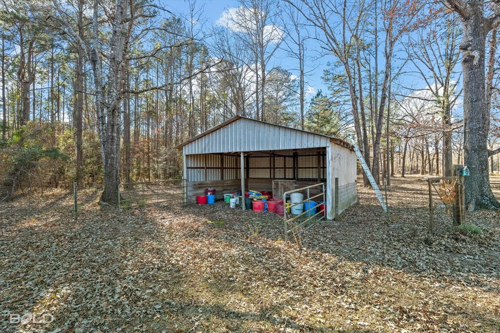 136 Scarborough Road Benton, LA 71006 - Photo 26 of 32 Open-sided shed with a metal roof and siding, set within a wooded area