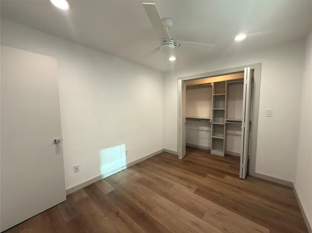 an empty room with wooden floor closet and windows