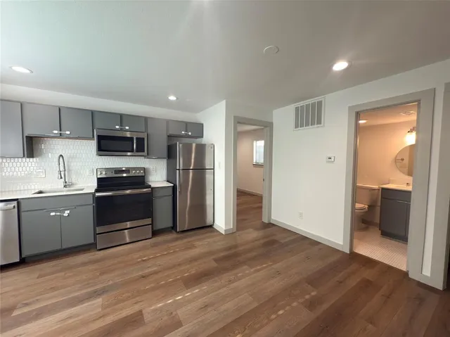 a kitchen with granite countertop a refrigerator and a stove top oven
