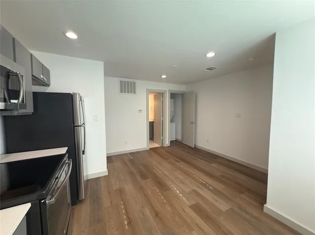 a view of an empty room with wooden floor and a fireplace