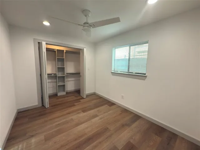 an empty room with wooden floor cabinet and windows