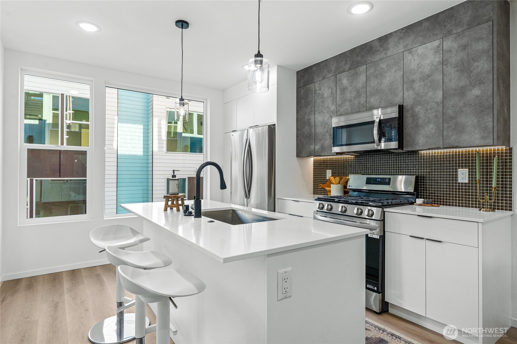 3510 Northeast 125th Street, Unit F Seattle, WA 98125 - Photo 14 of 24 a kitchen with stainless steel appliances a sink a stove a refrigerator a dining table and chairs with wooden floor