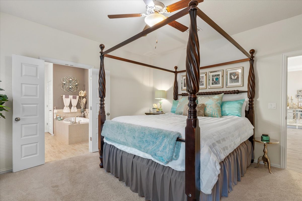 8721 Sikes Way Austin, TX 78747 - Photo 17 of 37 Bedroom with light colored carpet, connected bathroom, and a ceiling fan