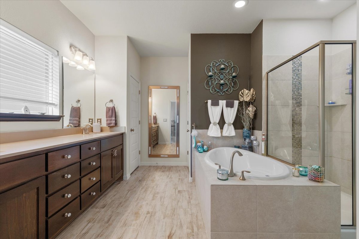 8721 Sikes Way Austin, TX 78747 - Photo 18 of 37 Full bath featuring a stall shower, vanity, a bath, and light wood-style flooring