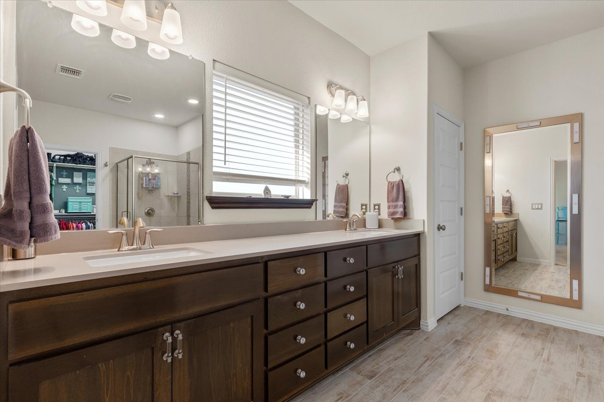 8721 Sikes Way Austin, TX 78747 - Photo 19 of 37 Full bathroom featuring double vanity, a shower stall, light wood finished floors, a closet, and connected bathroom