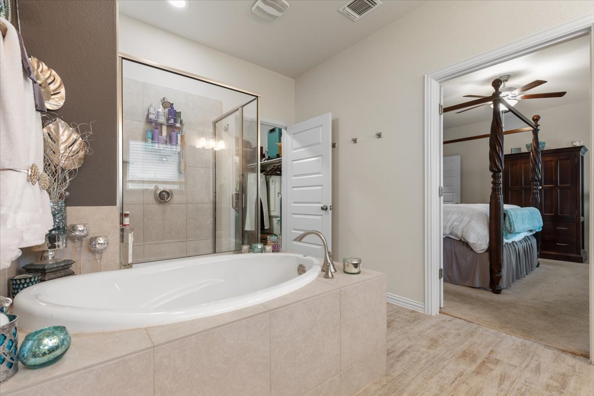 8721 Sikes Way Austin, TX 78747 - Photo 20 of 37 Full bath featuring a shower stall, ensuite bath, a ceiling fan, a garden tub, and light wood finished floors