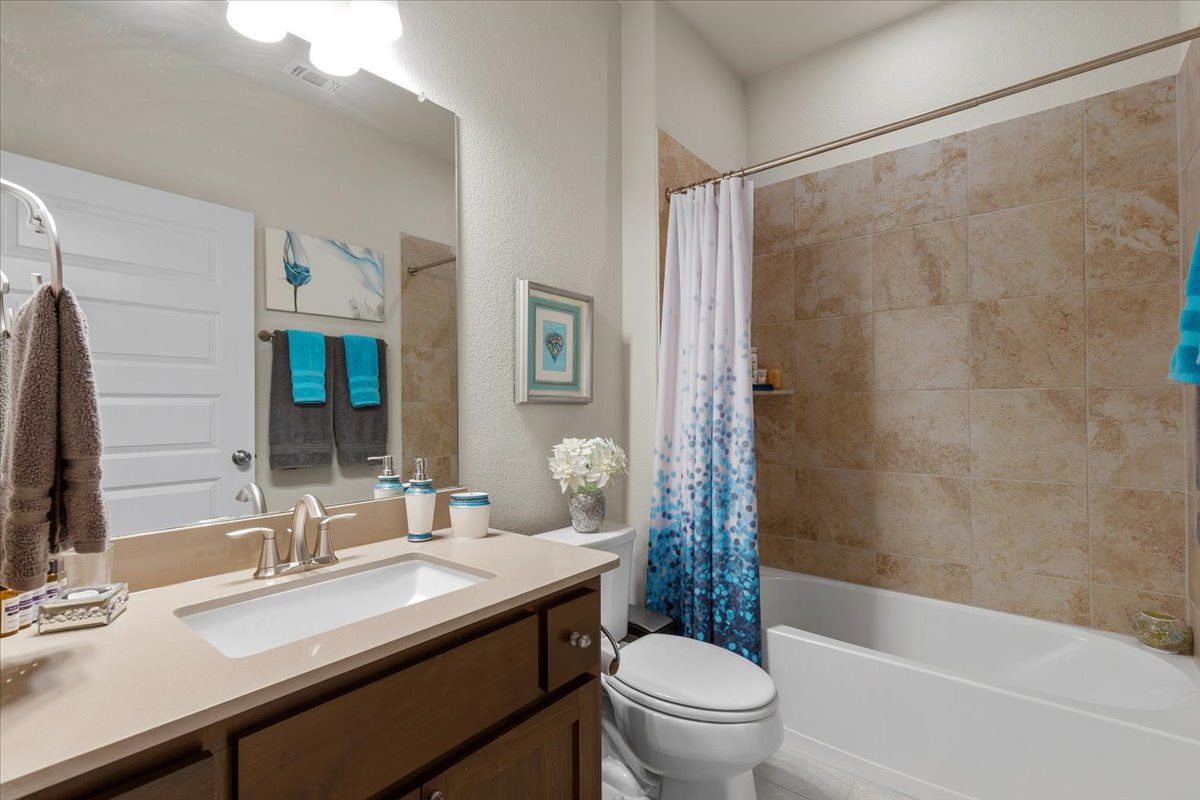 8721 Sikes Way Austin, TX 78747 - Photo 23 of 37 Full bathroom featuring vanity, shower / tub combo with curtain, and a textured wall