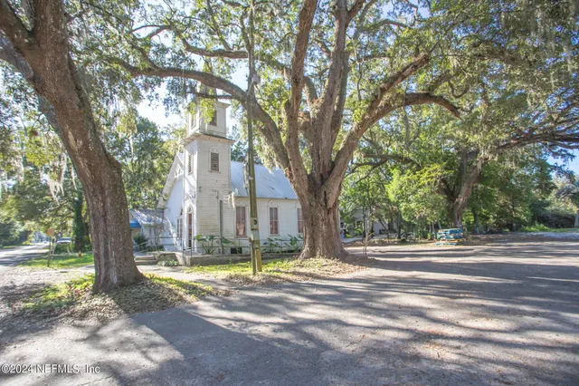 a view of a yard in front of a house with large trees