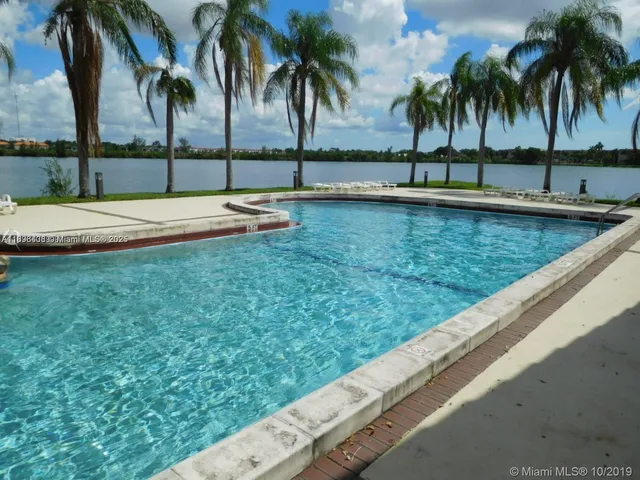 a view of swimming pool with a lawn chairs and palm tree