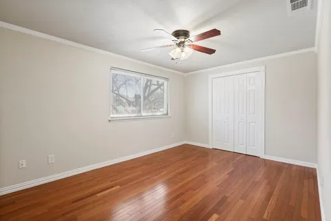a view of an empty room with window and wooden floor