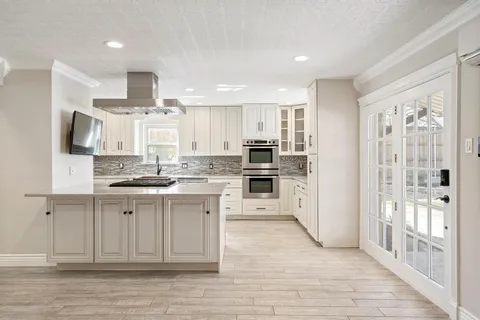 a large kitchen with kitchen island a sink dishwasher a stove and a refrigerator with wooden floor