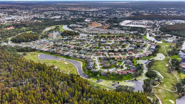 an aerial view of residential houses with outdoor space and trees