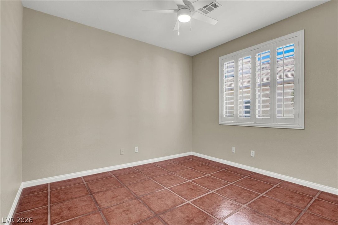 7308 Rustic Meadow Street Las Vegas, NV 89131 - Photo 14 of 27 A well-lit bedroom features classic plantation shutters and durable tile flooring.