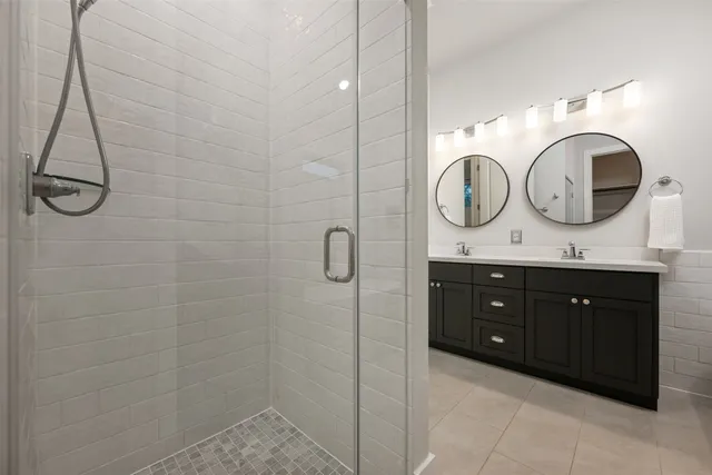 a bathroom with a double vanity sink mirror and shower