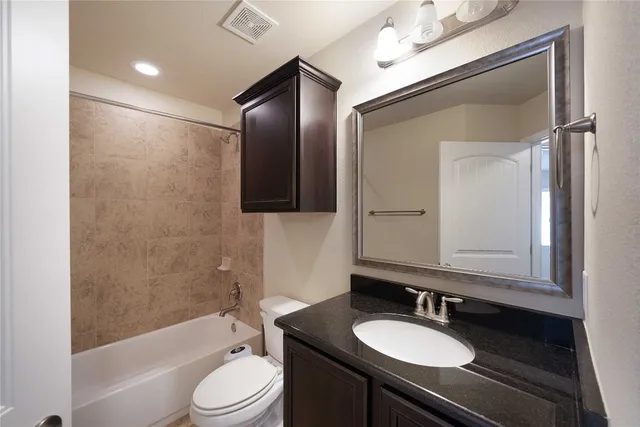 a bathroom with a granite countertop sink toilet a mirror and shower