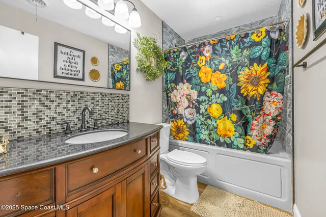a bathroom with a granite countertop sink and a toilet
