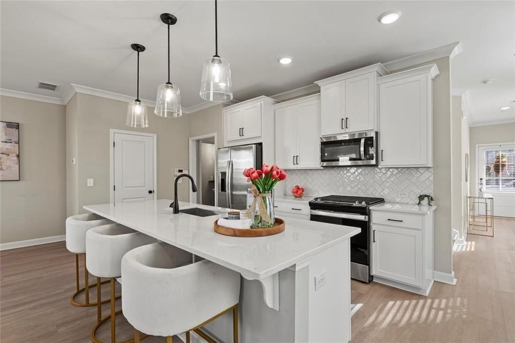 3739 Silvery Way Powder Springs, GA 30127 - Photo 5 of 28 a kitchen with kitchen island granite countertop a sink cabinets and wooden floor