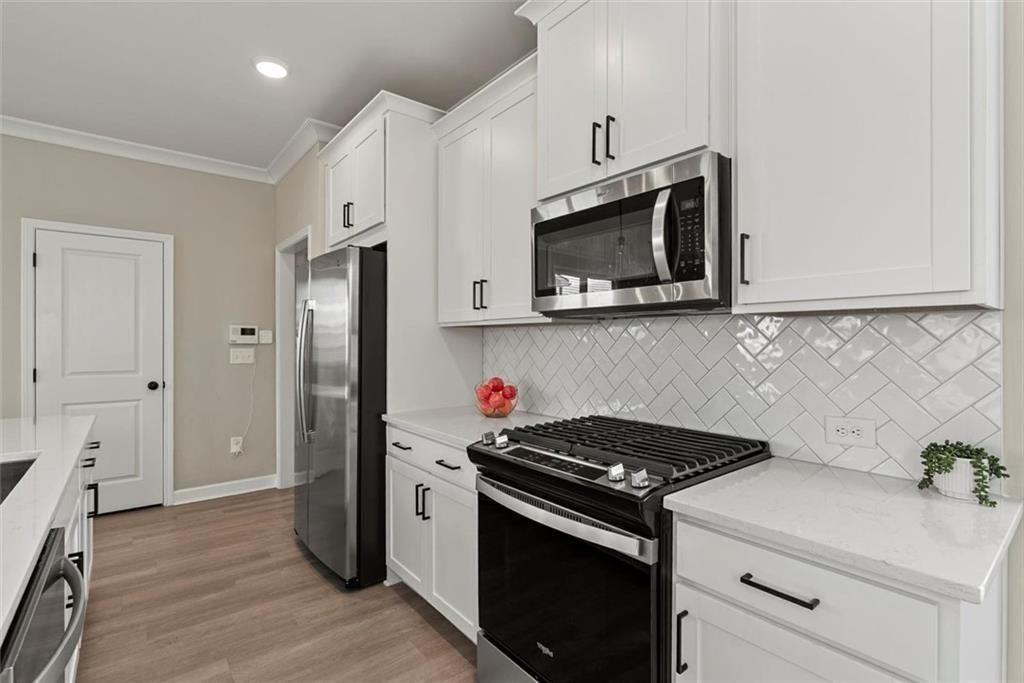 3739 Silvery Way Powder Springs, GA 30127 - Photo 9 of 28 a kitchen with stainless steel appliances white cabinets and stove