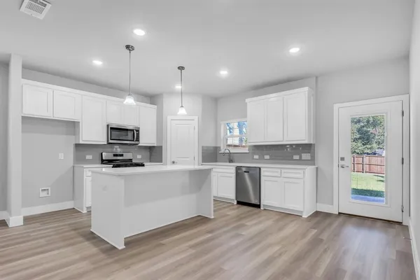 a kitchen with stainless steel appliances a stove top oven a sink a refrigerator a center island and cabinets