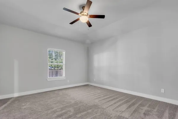an empty room with a window and a fan