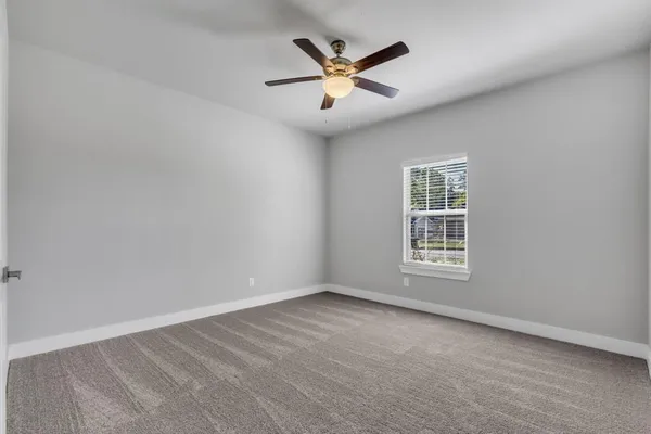 an empty room with ceiling fan and windows