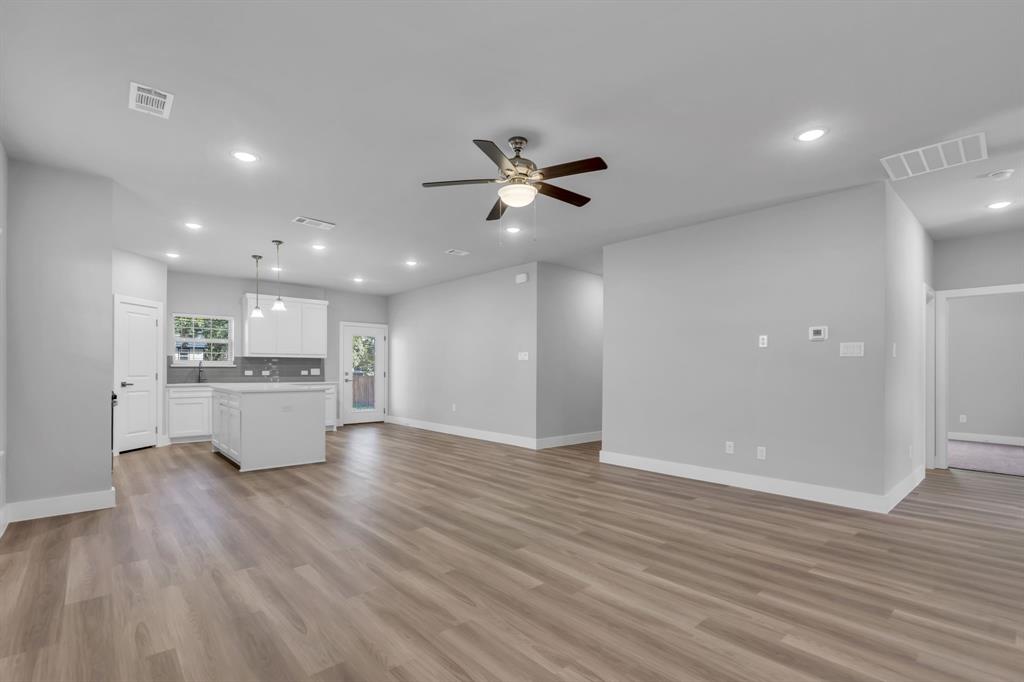 121 West Morton Street Denison, TX 75021 - Photo 8 of 28 a view of an empty room and kitchen with wooden floor