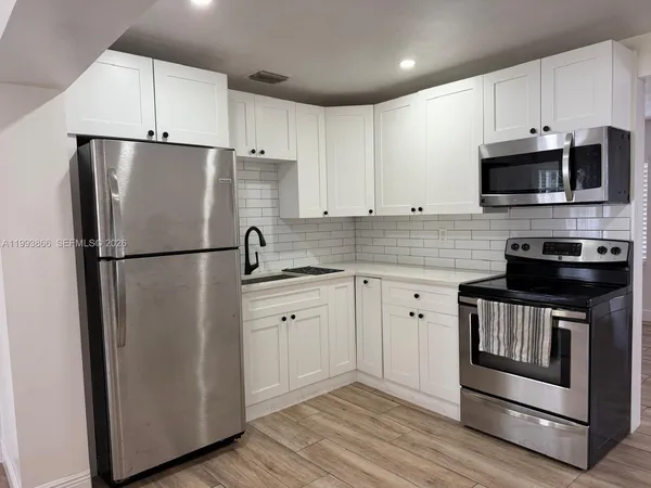 a kitchen with stainless steel appliances white cabinets white stove a refrigerator and a microwave