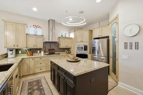 a kitchen with granite countertop stainless steel appliances a stove refrigerator sink and cabinets