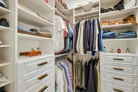 a view of walk in closet with clothes and shoes