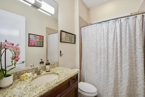 a bathroom with a granite countertop sink vanity mirror and toilet