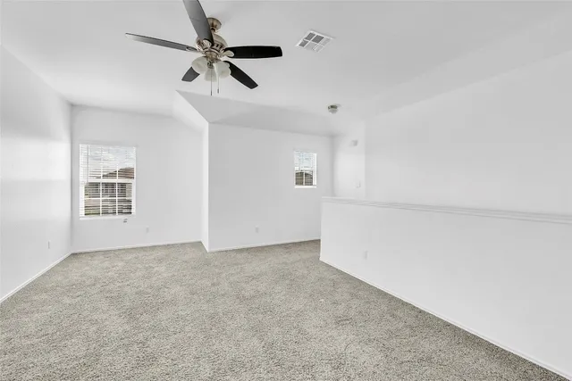 an empty room with windows and ceiling fan