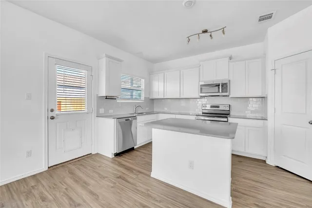 a kitchen with stainless steel appliances a sink a stove a refrigerator cabinets and a window