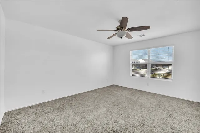an empty room with windows and ceiling fan
