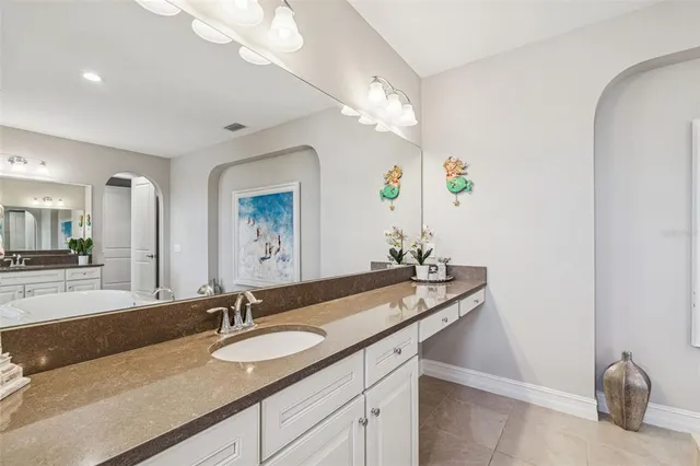 a bathroom with double vanity sinks a vanity a lamp and a mirror