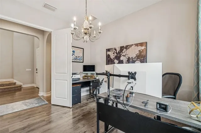 a dining room with wooden floor a chandelier a wooden table and chairs