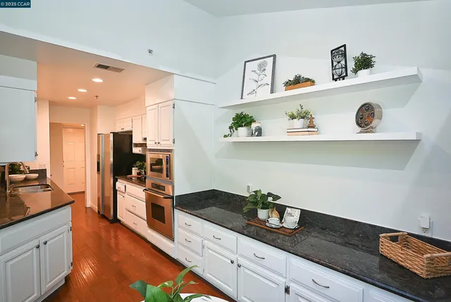 a kitchen with stainless steel appliances granite countertop a lot of cabinets a stove and wooden floor