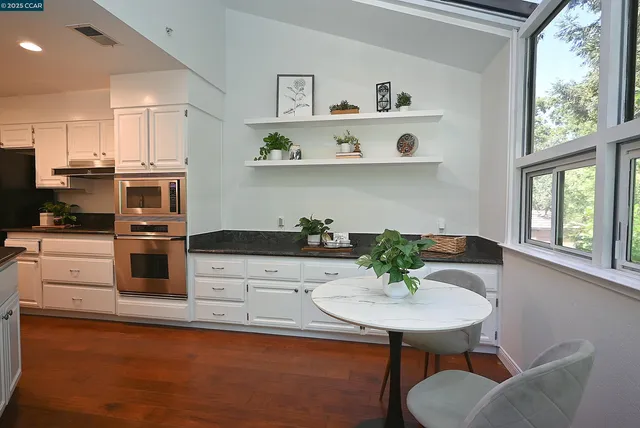 a kitchen with stainless steel appliances a table chairs and microwave