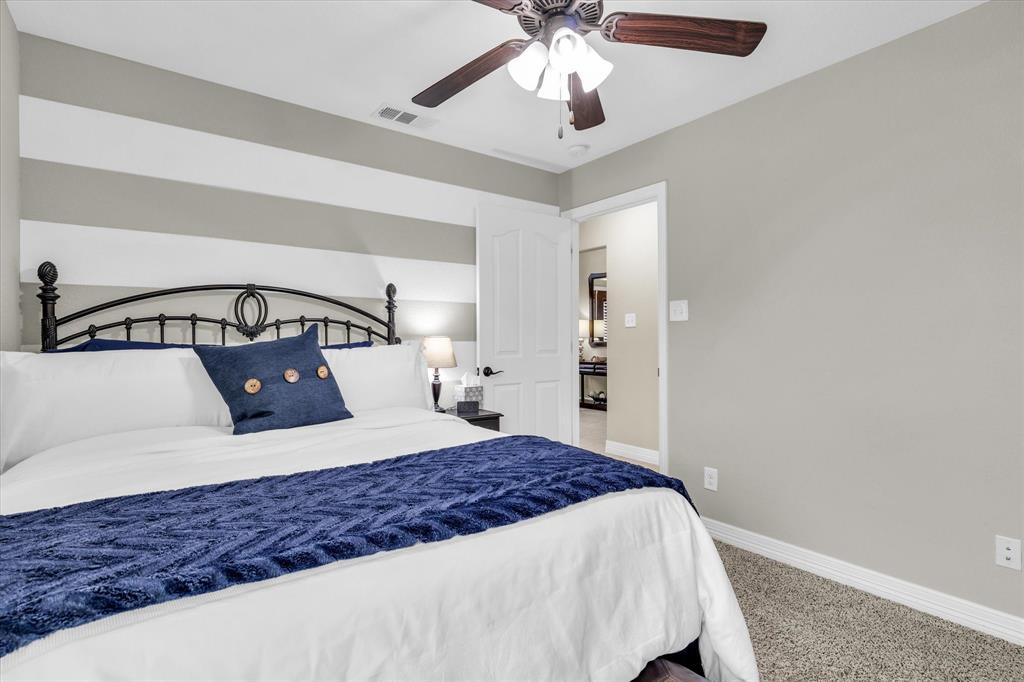 910 Springdale Lane Lorena, TX 76655 - Photo 20 of 39 Bedroom featuring neutral carpeting, light gray walls with a horizontal striped accent wall, a white paneled door, and a ceiling fan with light fixture