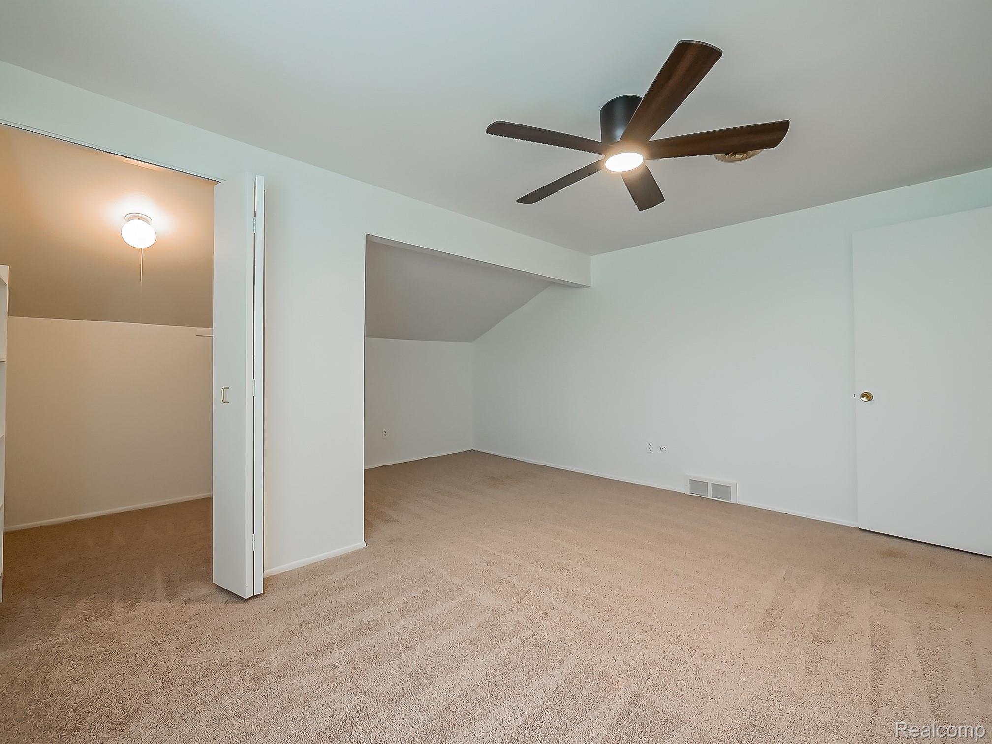 42195 Park Ridge Road Novi, MI 48375 - Photo 24 of 52 Neutral tone wall paint, textured carpet flooring, ceiling fan with integrated lighting, door with brass hardware, sloped ceiling architectural detail